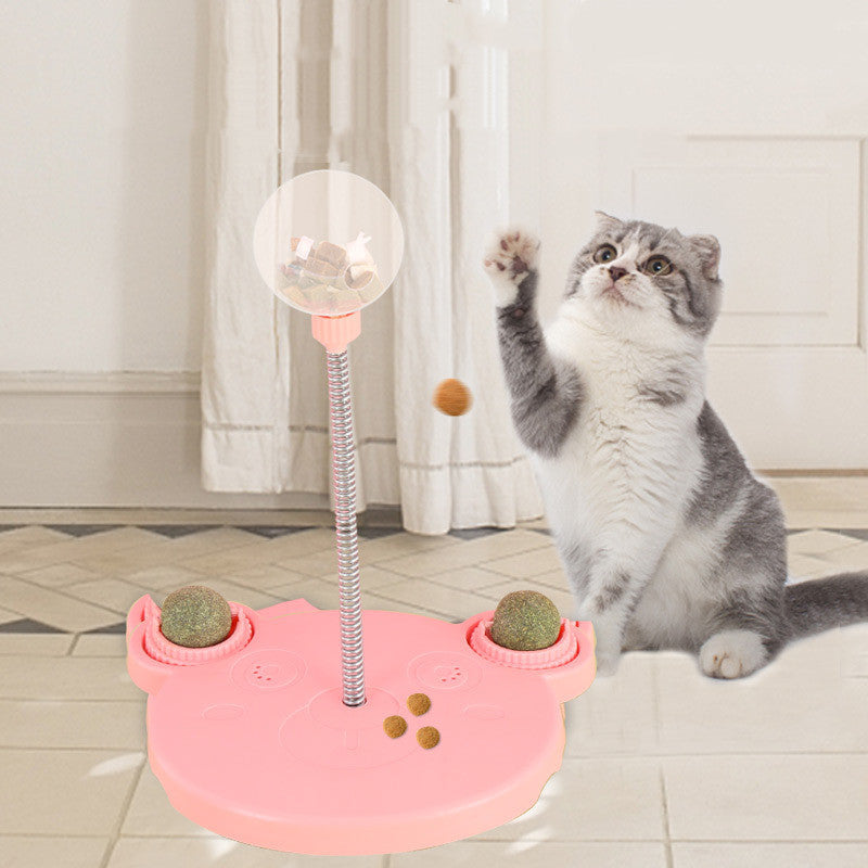 Orange Poppy pink interactive cat feeder toy with spring bounce ball and two treat cups shown with a playful gray cat