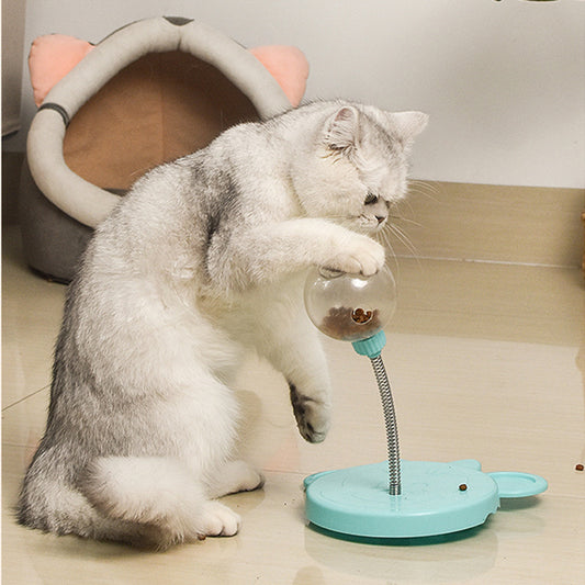 Orange Poppy interactive cat feeder toy with turquoise base and clear treat ball on spring with gray and white cat pawing