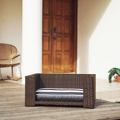 Ochre Menoetius brown rattan dog bed with cushion placed on wooden deck outdoors
